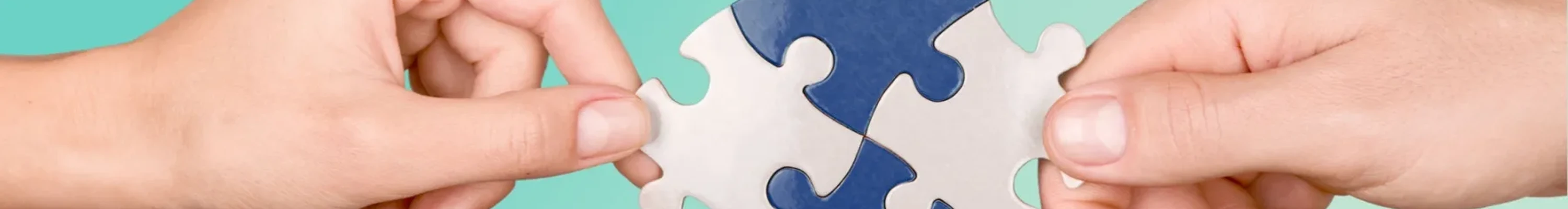 Jigsaw puzzle pieces being put together and held by two hands