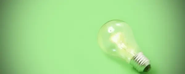 single screw fit glowing lightbulb on a green background