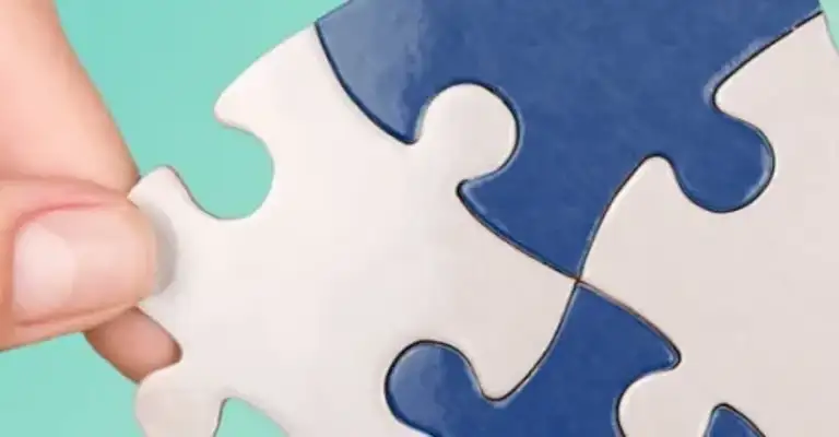 Jigsaw puzzle pieces being put together and held by two hands