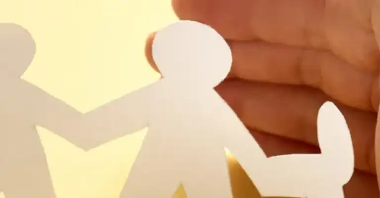 hands curved around paper cut out people in circle (resized)