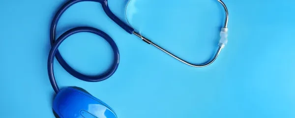 Blue stethoscope attached to computer mouse blue background