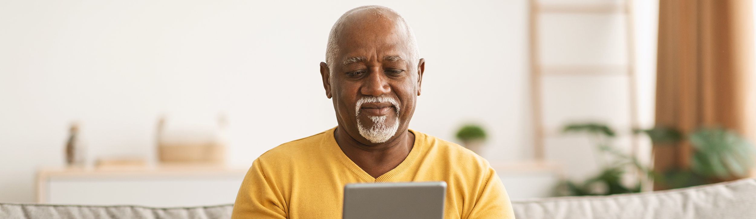 Man With Tablet On Sofa Yellow Jumper Web