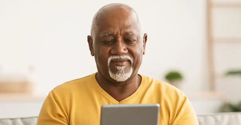 Man With Tablet On Sofa Yellow Jumper Web