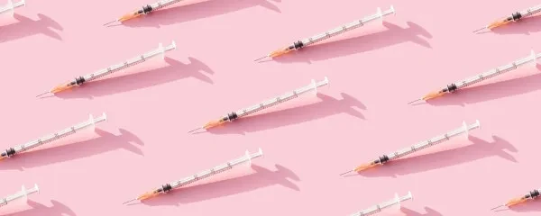 Multiple immunisation needles on a pink background