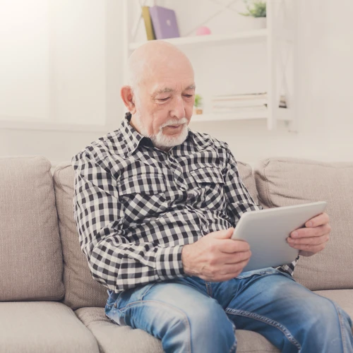 Older Man On Tablet Sitting On Sofa Web