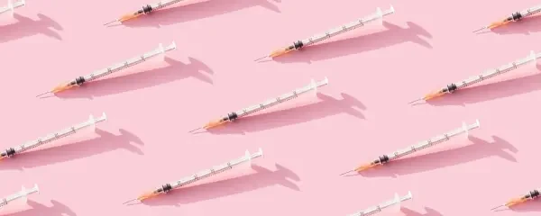 Multiple immunisation needles on a pink background