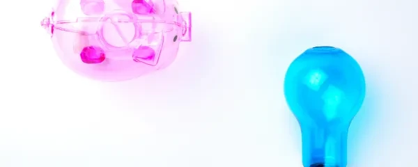 small transparent pink piggy bank and blue lightbulb