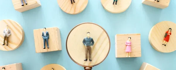 Wooden toy people under a magnifying glass