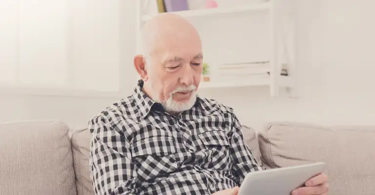 Older Man Sitting On Sofa Check Shirt Web